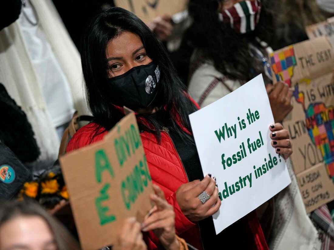 Protestors hold signs saying 'Why is the fossil fuel industry inside?'
