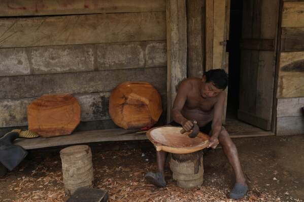 Pedro Chami carves a gold-panning dish made of wood in Villa Caleta, a community in Panama that used to benefit economically by being on the route migrants took after crossing the Darien Gap on their way north to the U.S., Monday, April 7, 2025. (AP Photo/Matias Delacroix)
