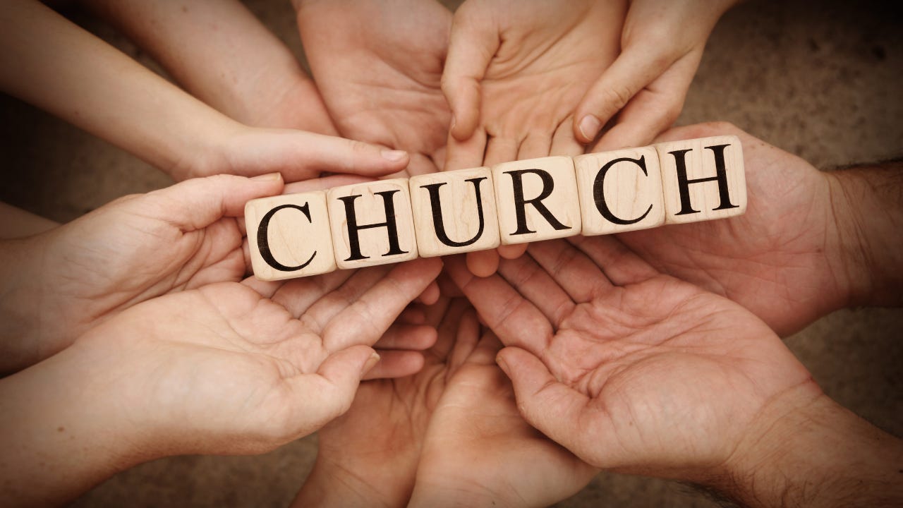 People's hands holding wooden blocks that spell "Church."