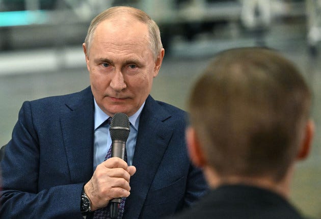 Russian President Vladimir Putin holds a microphone.