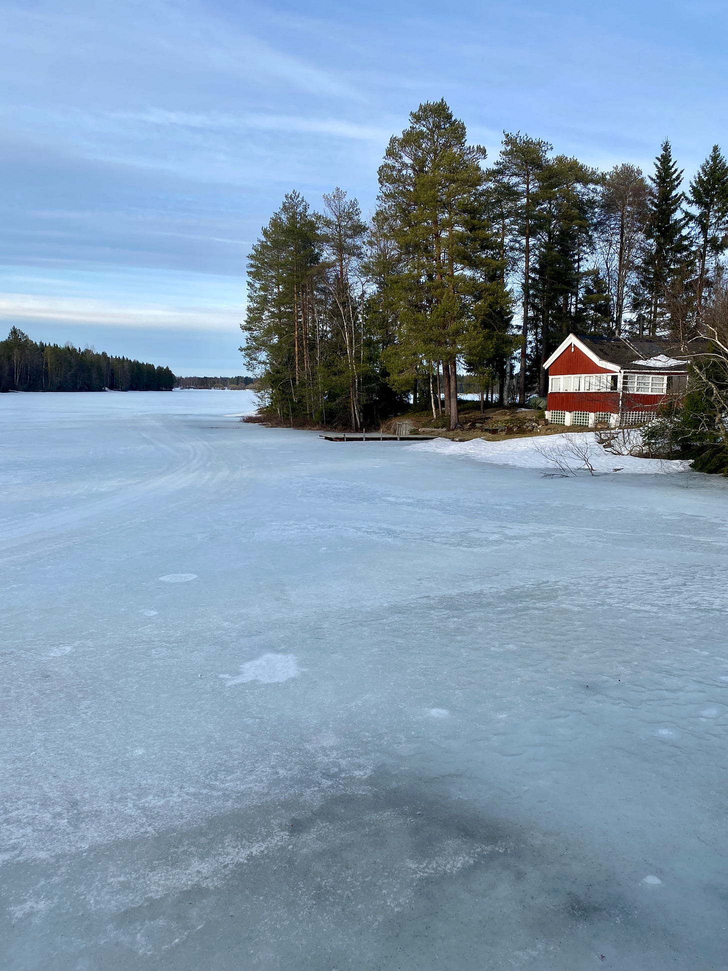 Large frozen lake, with a small red cottage on the shore