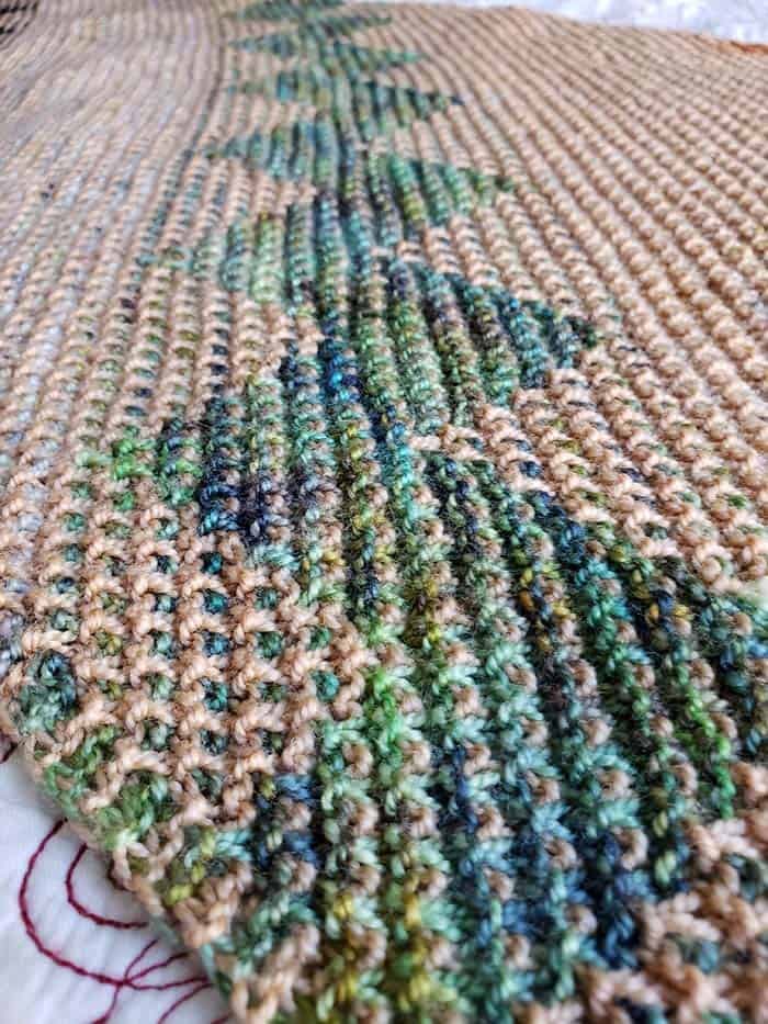 Close up of the mosaic section knitted with the KPPM yarn of different shades of green and blue