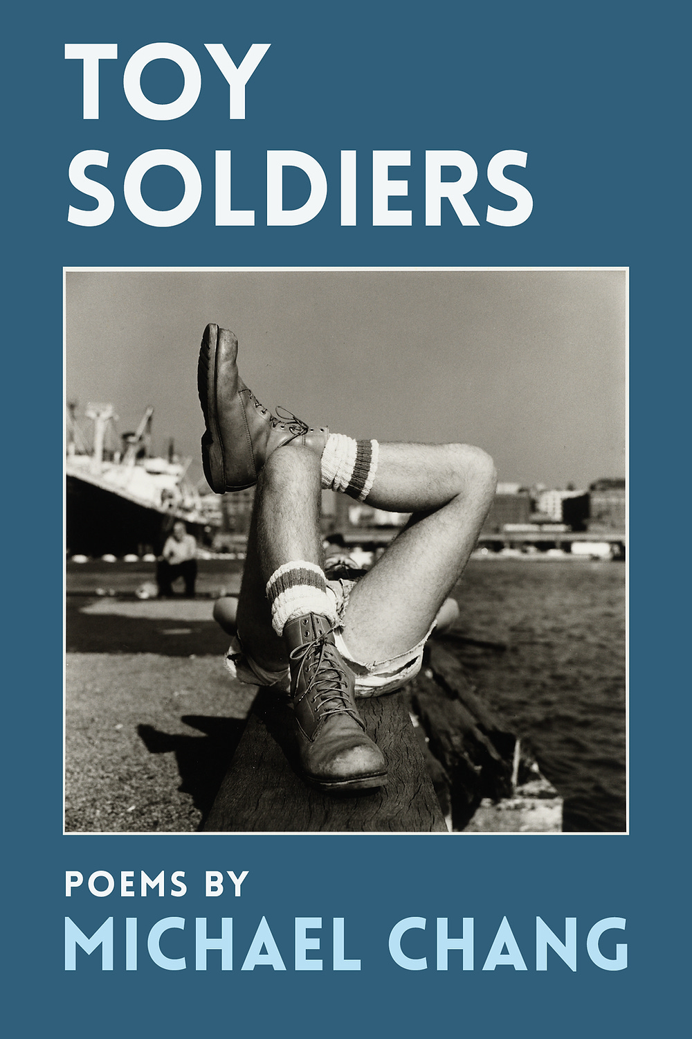 Cover of TOY SOLDIERS by MICHAEL CHANG, white text on a dark blue background. the center of the cover has a photo of someone lying on their back on a dock, only their shoes and socks are visible to the camera