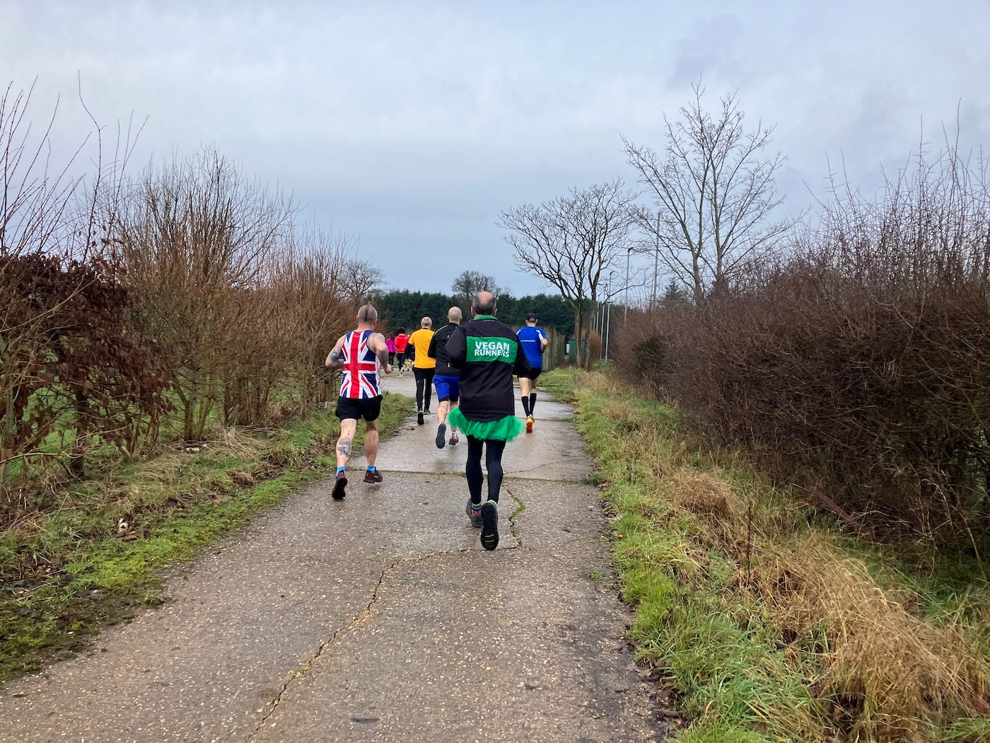 Runners on a concrete section of path between scrubland.