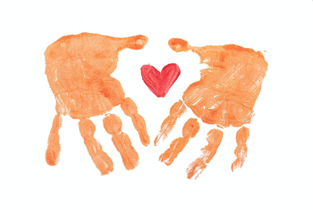 imprint in paint of two splayed hands enclosing a drawn red heart