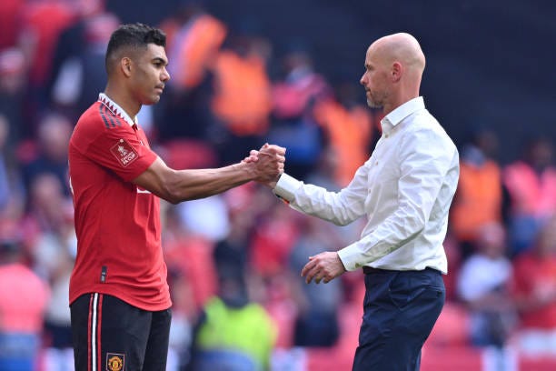 Manchester United's Dutch manager Erik ten Hag consoles Manchester United's Brazilian midfielder Casemiro on the pitch after the English FA Cup final...