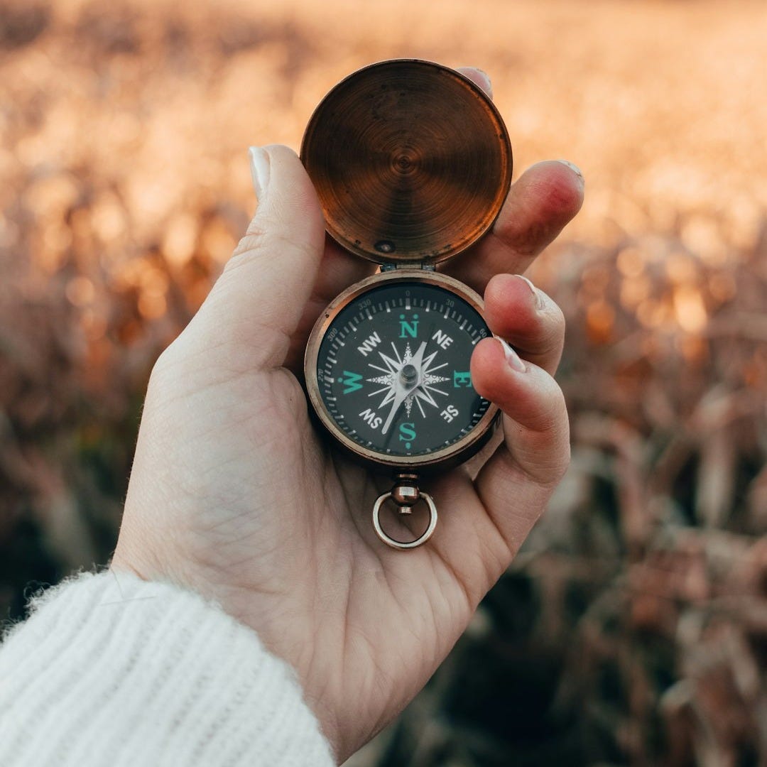 person holding green and gold compass person holding green and gold compass