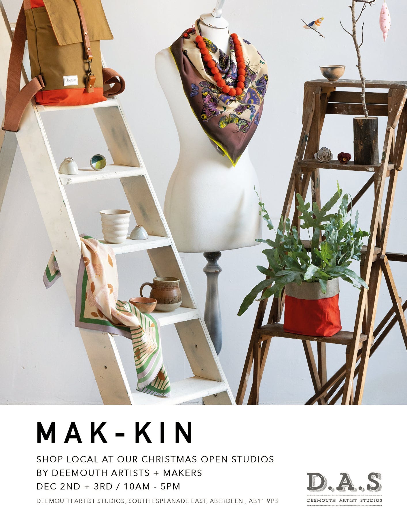 A promotional poster for "MAK-KIN," an event for shopping locally at Christmas open studios by Deemouth Artists + Makers. It showcases a creatively arranged display with an artist's mannequin dressed in a jacket and a colourful scarf, accessorised with chunky necklaces. Beside it, on a wooden stool, there's a potted plant in a two-tone fabric pot, and a small wooden ladder holds a cushion and a few ceramic pieces. A bird and a fish ornament hang in the background, adding a whimsical touch. The event details at the bottom invite visitors to Deemouth Artist Studios on December 2nd and 3rd from 10 am to 5 pm. The address provided is South Esplanade East, Aberdeen, AB11 9PB.