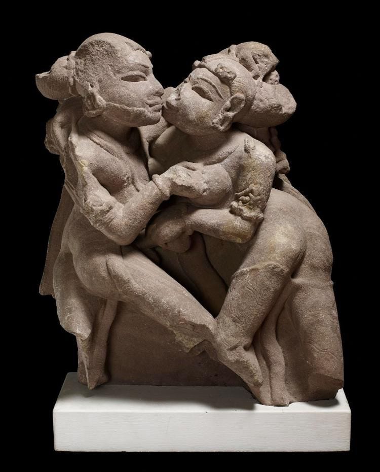 Image of red sandstone sculpture depicting two lovers.
