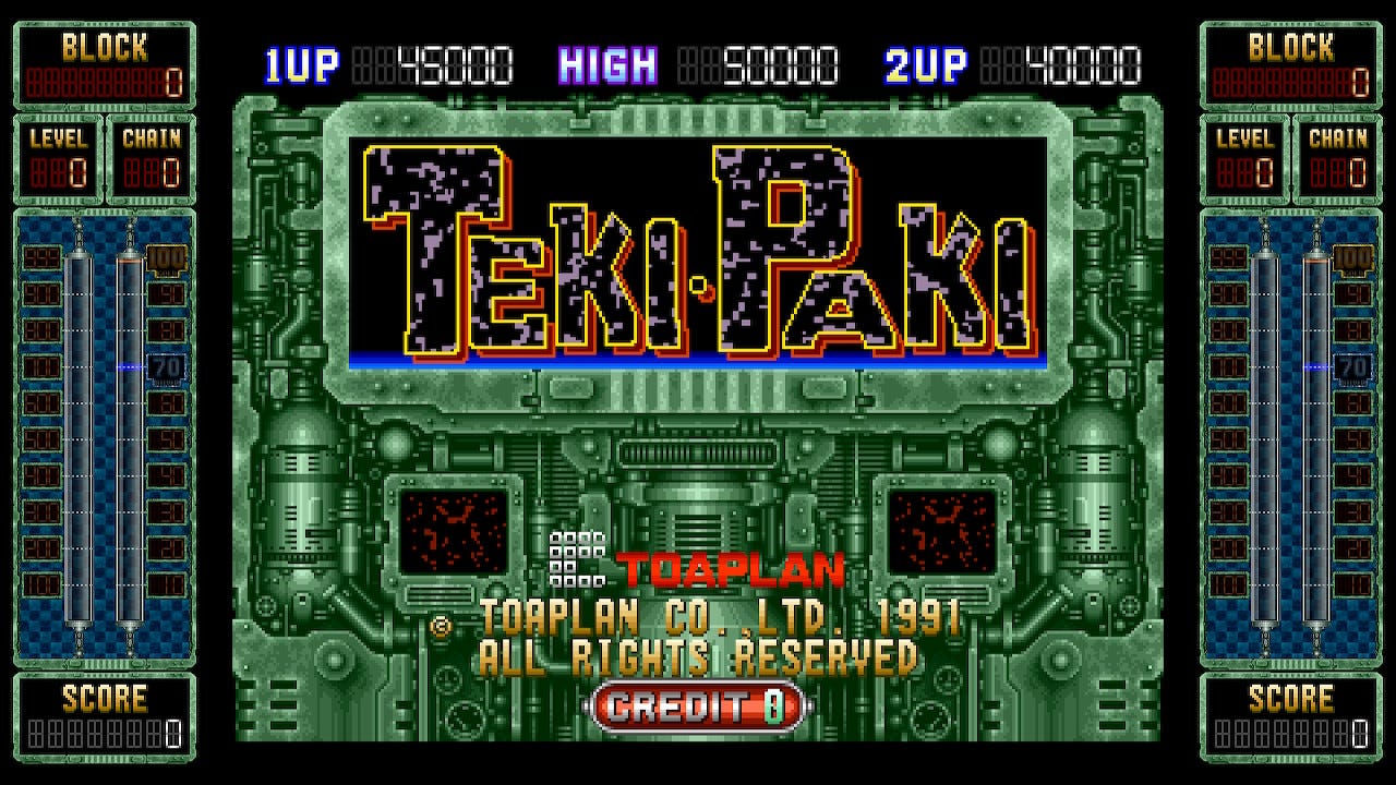 A screenshot of the title screen for Teki Paki, which features the game's logo on the largest monitor of a huge, sci-fi style computer with industrial elements to it. It fits the game's general robots/industry vibe quite well.