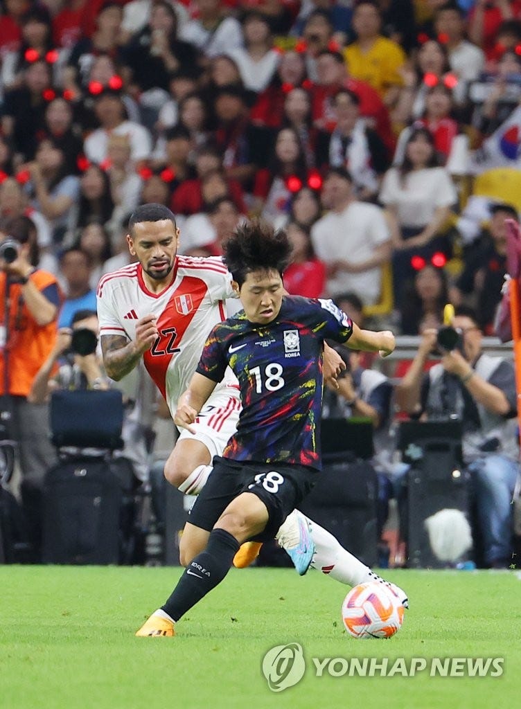 Lee Kang-in of South Korea (R) battles Alexander Callens of Peru for the ball during the teams' friendly football match at Busan Asiad Main Stadium in Busan, 320 kilometers southeast of Seoul, on June 16, 2023. (Yonhap)