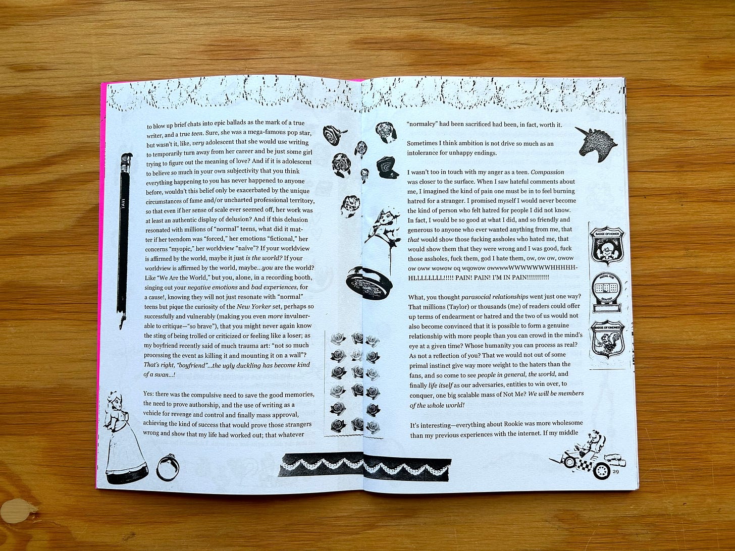 A photograph showing an open copy of the zine “Fan Fiction” laid flat on a wooden surface. Two pages of the zine are visible. The text is written in a serif font and the borders of both pages are decorated with miscellaneous images which include pictures of rings, sticker sheets, pieces of lace, an image of a pencil, and images showing a distorted Princess Peach figurine. 