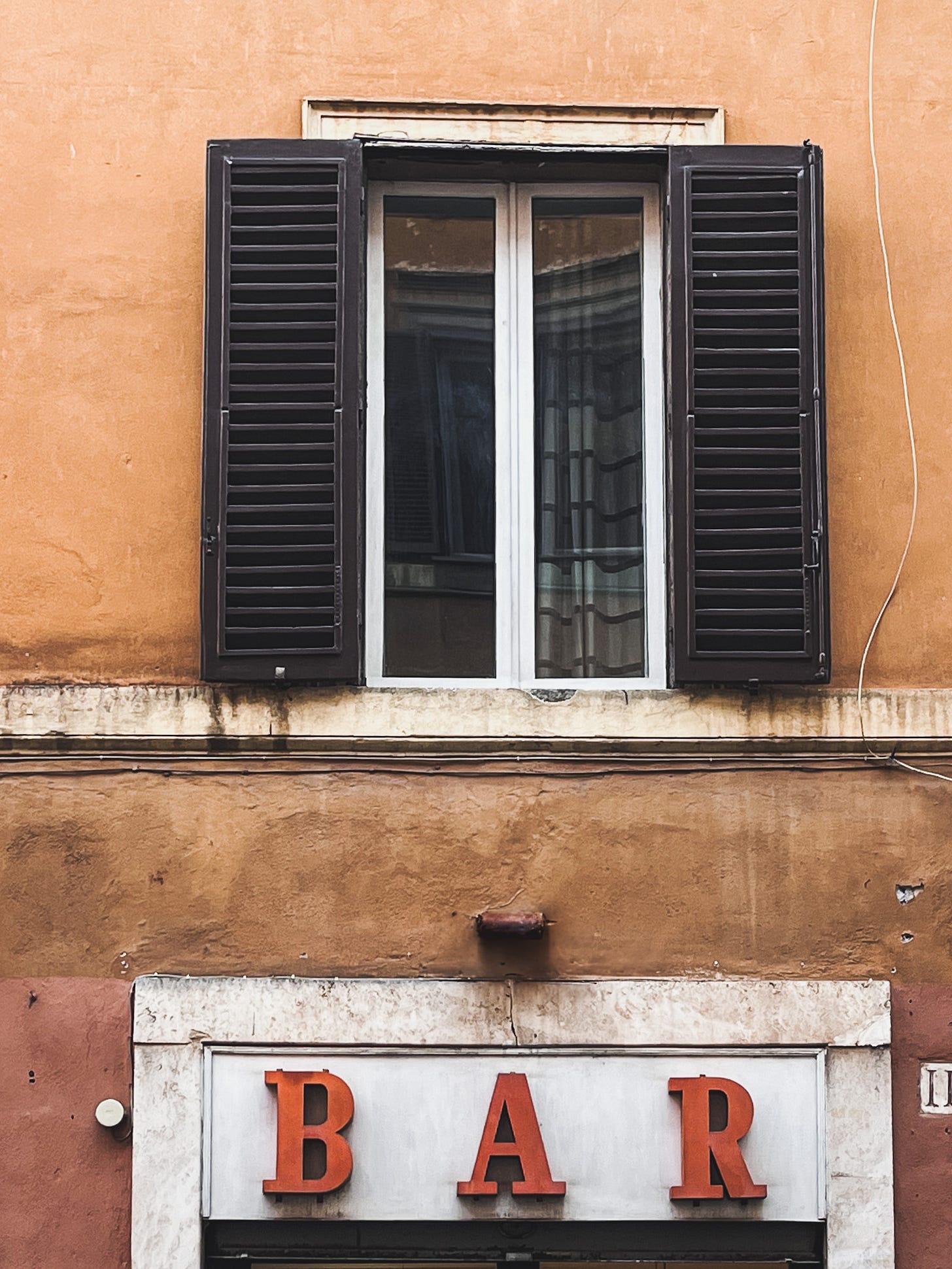 vintage Italian bar sign with bold red letters on a weathered ochre building with dark shutters vintage Italian bar sign with bold red letters on a weathered ochre building with dark shutters