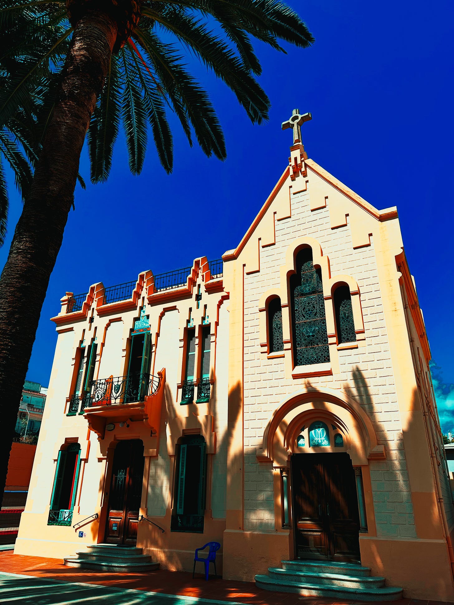 Shadows of Serenity - A peaceful Sitges building basking under palm trees and a deep blue sky.