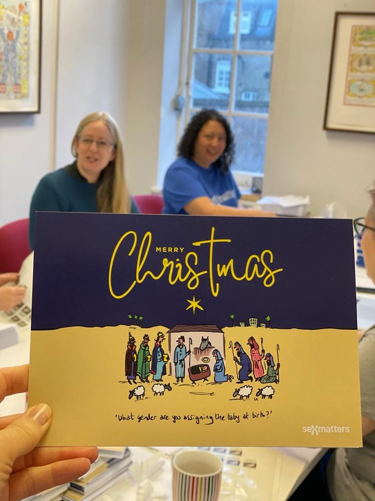 Sex Matters Christmas card with a Grizelda drawing of the Nativity and the caption “What gender are you assigning the baby at birth?”. Helen Joyce and Maya Forstater sit in the background