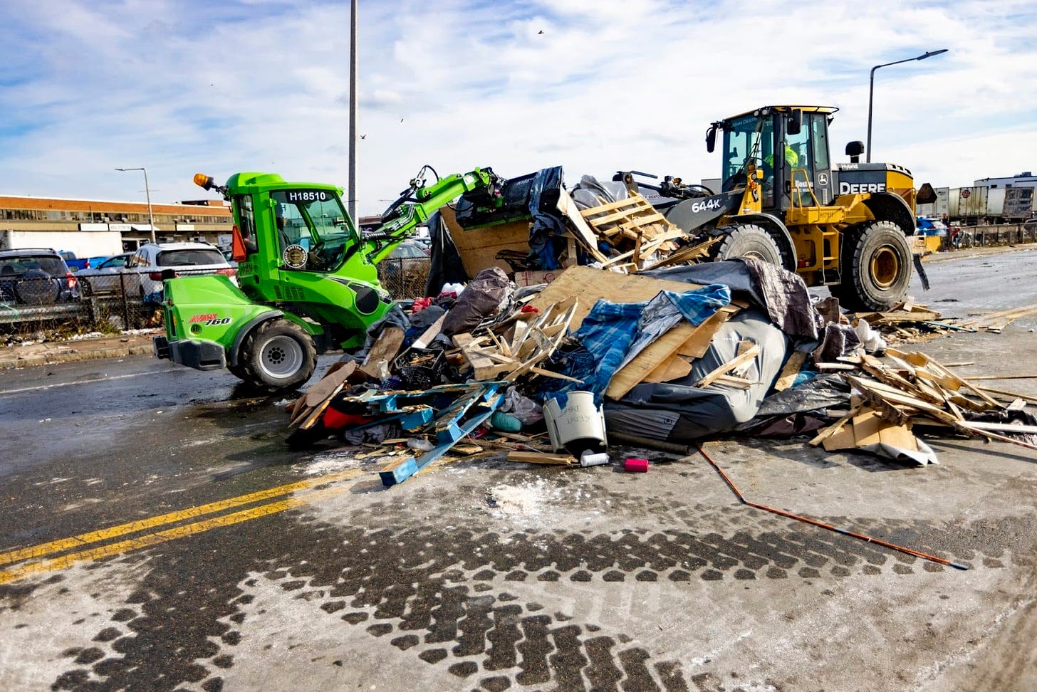 Two land mover trucks remove a pile of debris from an encampment near the intersection of Massachusetts Avenue and Melnea Cass Boulevard in 2022