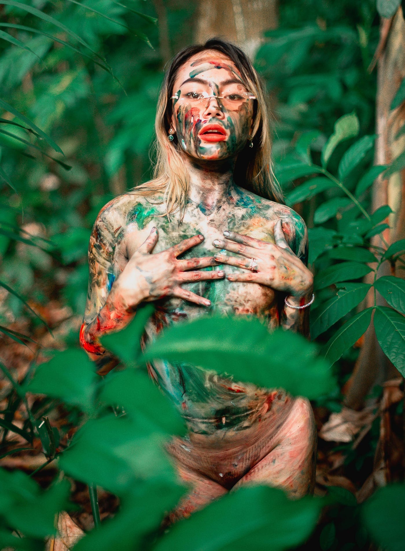 Woman with glasses in jungle fronds and body paint