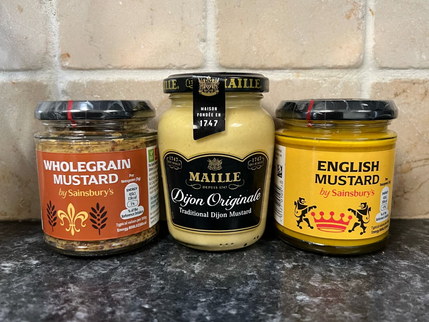 A photo of three jars. Wholegrane, Dijon and English mustard.