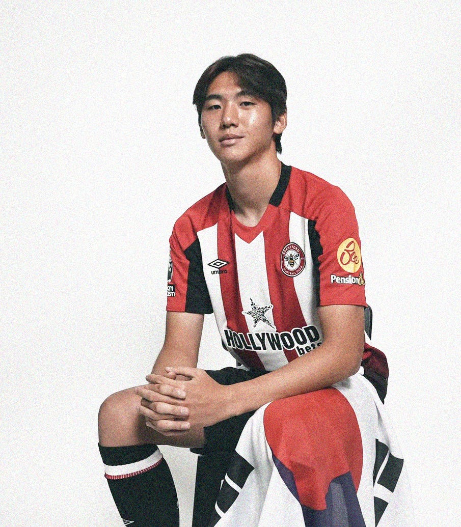 A photo of Kim Ji-soo in a Brentford home kit, sat on a box with a South Korea flag draped over his left knee