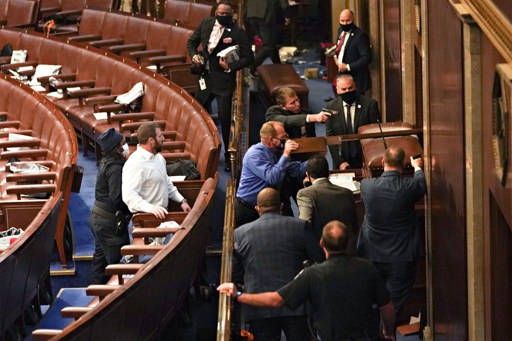 U.S. Capitol police officers point guns at a door during a joint session of Congress to count the votes of the 2020 presidential election takes place in the House Chamber in Washington, D.C., U.S., on Wednesday, Jan. 6, 2021. The U.S. Capitol was placed under lockdown and Vice President Mike Pence left the floor of Congress as hundreds of protesters swarmed past barricades surrounding the building where lawmakers were debating Joe Biden's victory in the Electoral College. Photographer: Stefani Reynolds/Bloomberg via Getty Images
