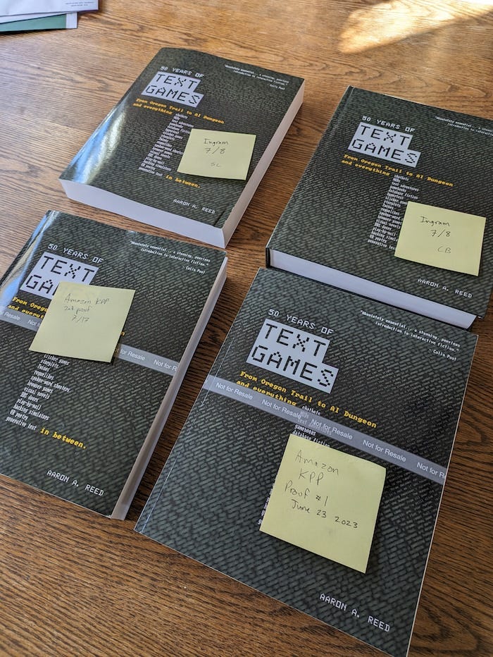 Four copies of "50 Years of Text Games" laid out side by side, with sticky notes on the covers identifying each book's origin.