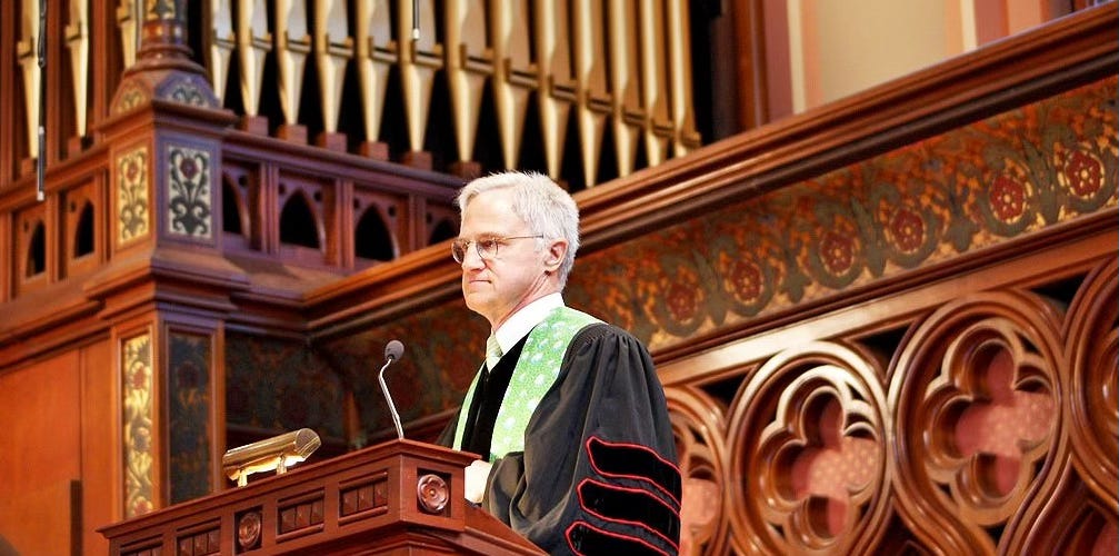 Male minister standing in pulpit looking out over congregation.