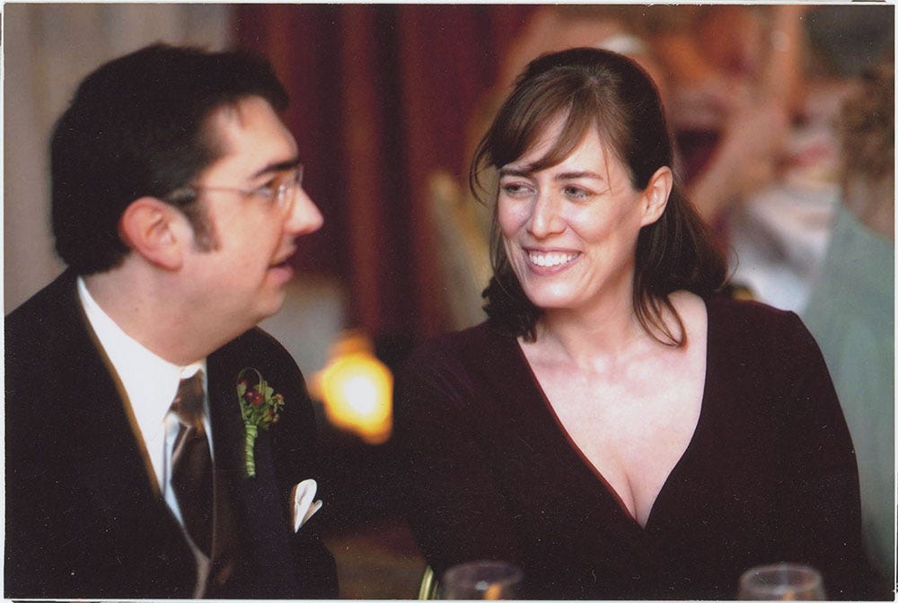 A picture of the co-founders of Socratica, Michael Harrison (wearing a suit and speaking) and Kimberly Hatch Harrison (wearing a dress and smiling)