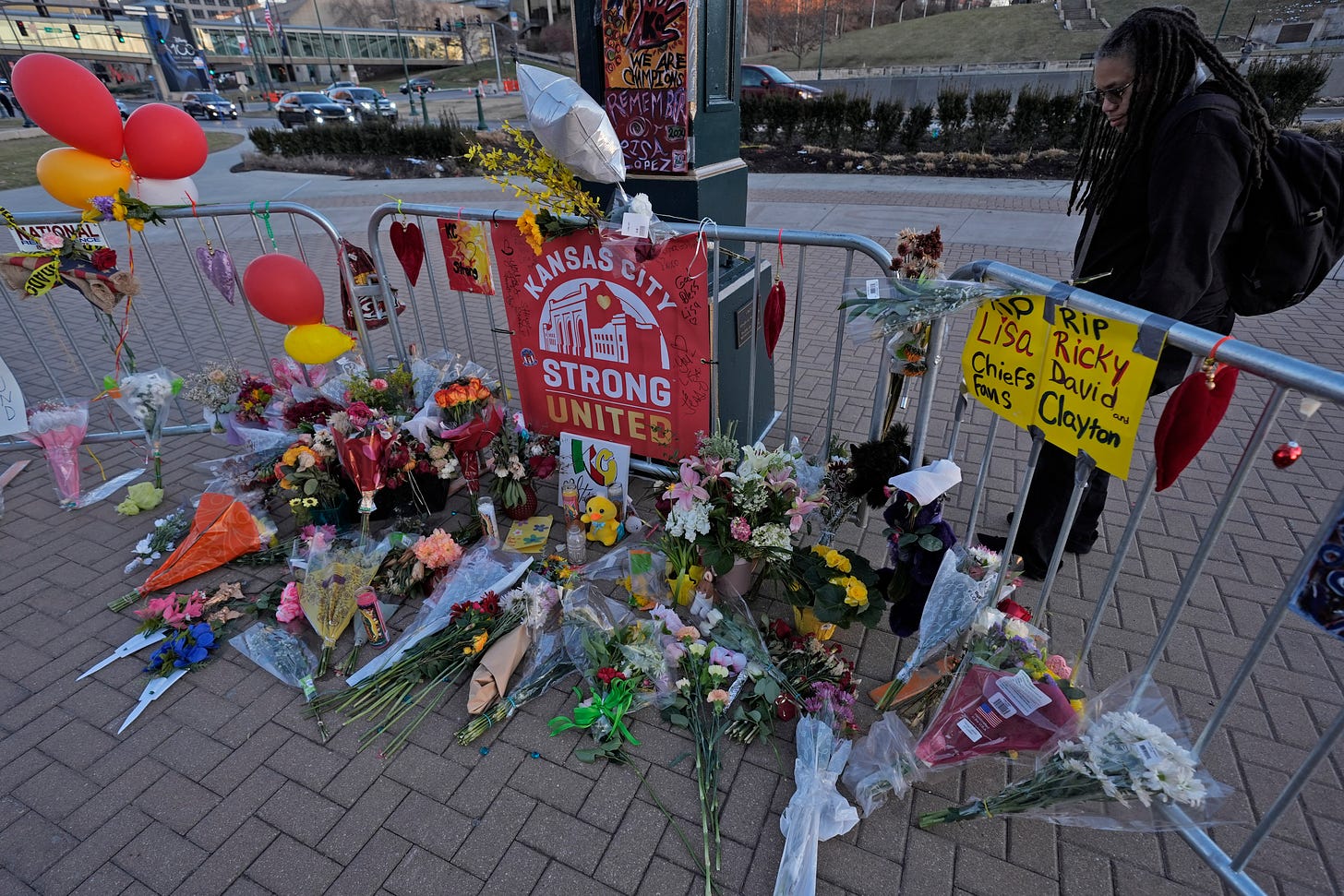 A memorial for victims of the mass shooting in Kansas City with a red ''Kansas City Strong United'' sign and several bouquets of flowers. 