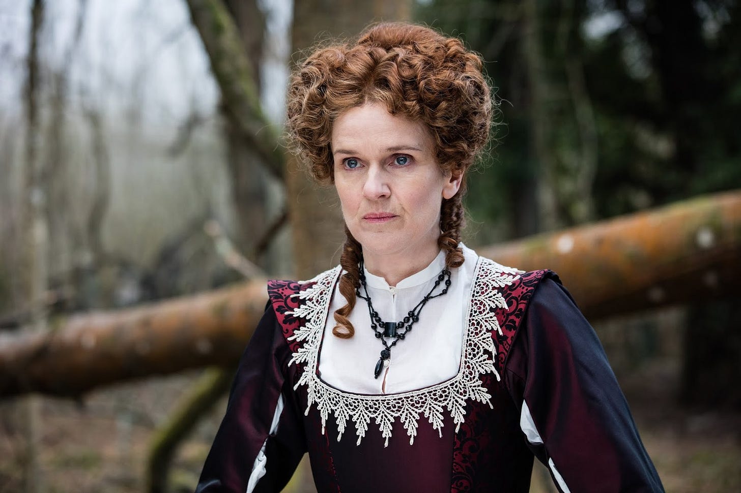 This image shows Becka Savage (played by Siobhan Finneran) standing in front of a downed tree trunk in "The Witchfinders" (Doctor Who Series 11's eighth episode). This image shows Becka Savage (played by Siobhan Finneran) standing in front of a downed tree trunk in "The Witchfinders" (Doctor Who Series 11's eighth episode).