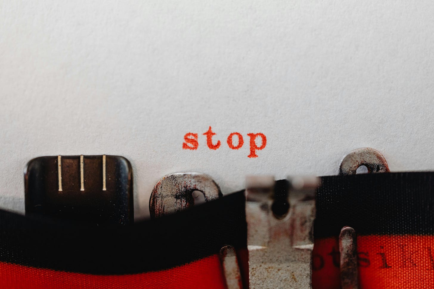 The word “stop” typed in red on a white page by a typewrite.