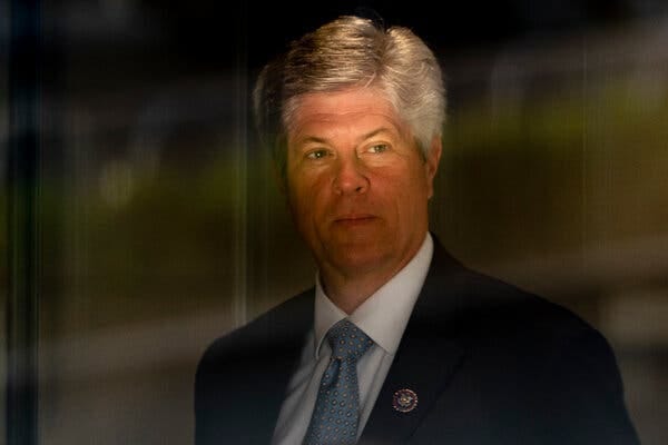 Former Representative Jeff Fortenberry stands in a dimly lit area with a light blue tie and dark suit, with his congressional pin on his lapel, in March 2022.