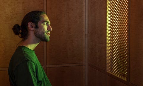 A person converses with the AI Jesus through a latticework screen