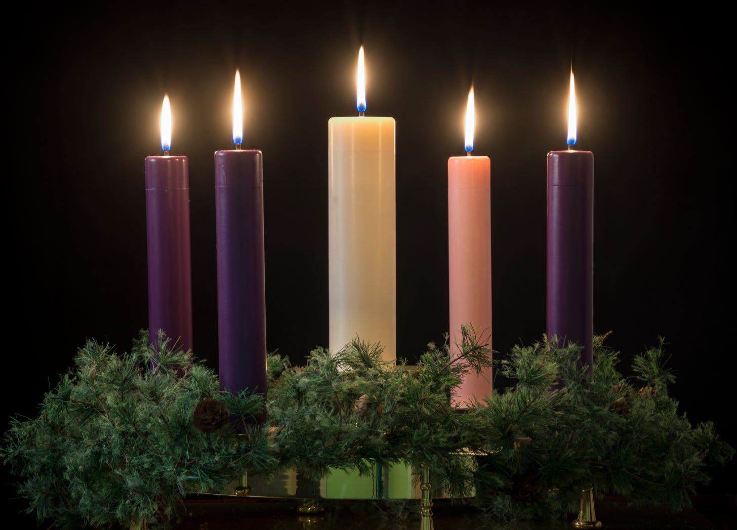 An Avent Wreath with three purple, one pink, and one white candle, plus evergreens