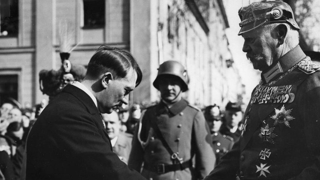 Hitler, left, bows his head while shaking hands with Von Hindenburg