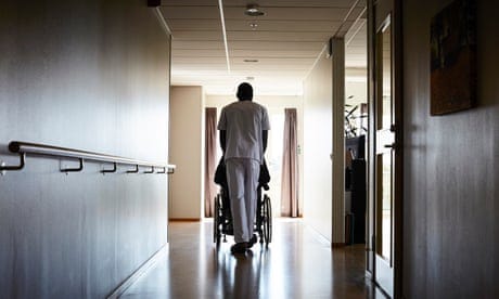 Full length rear view of male nurse pushing senior man on wheelchair at hospital corridor<br>Full length rear view of male nurse pushing senior man on wheelchair at hospital corridor - stock photo