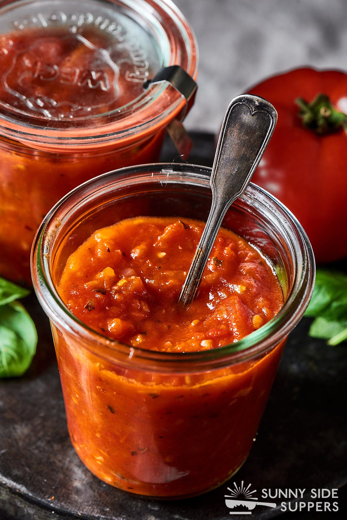 A jar filled with homemade pasta sauce and a spoon.