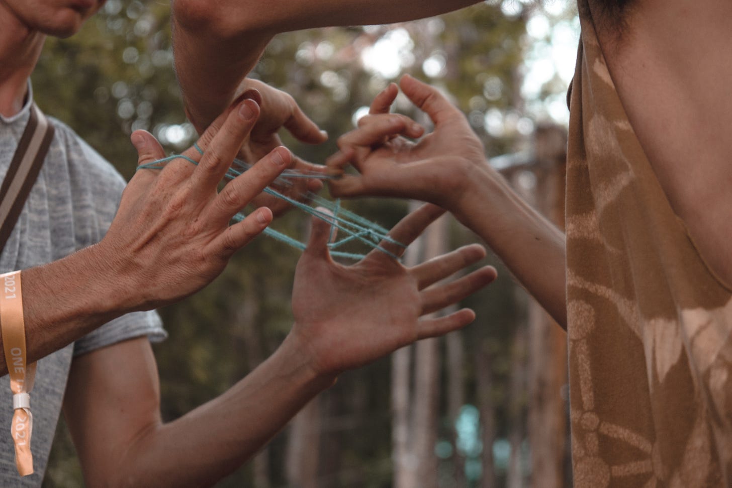 hands of two people building a cat's cradle together