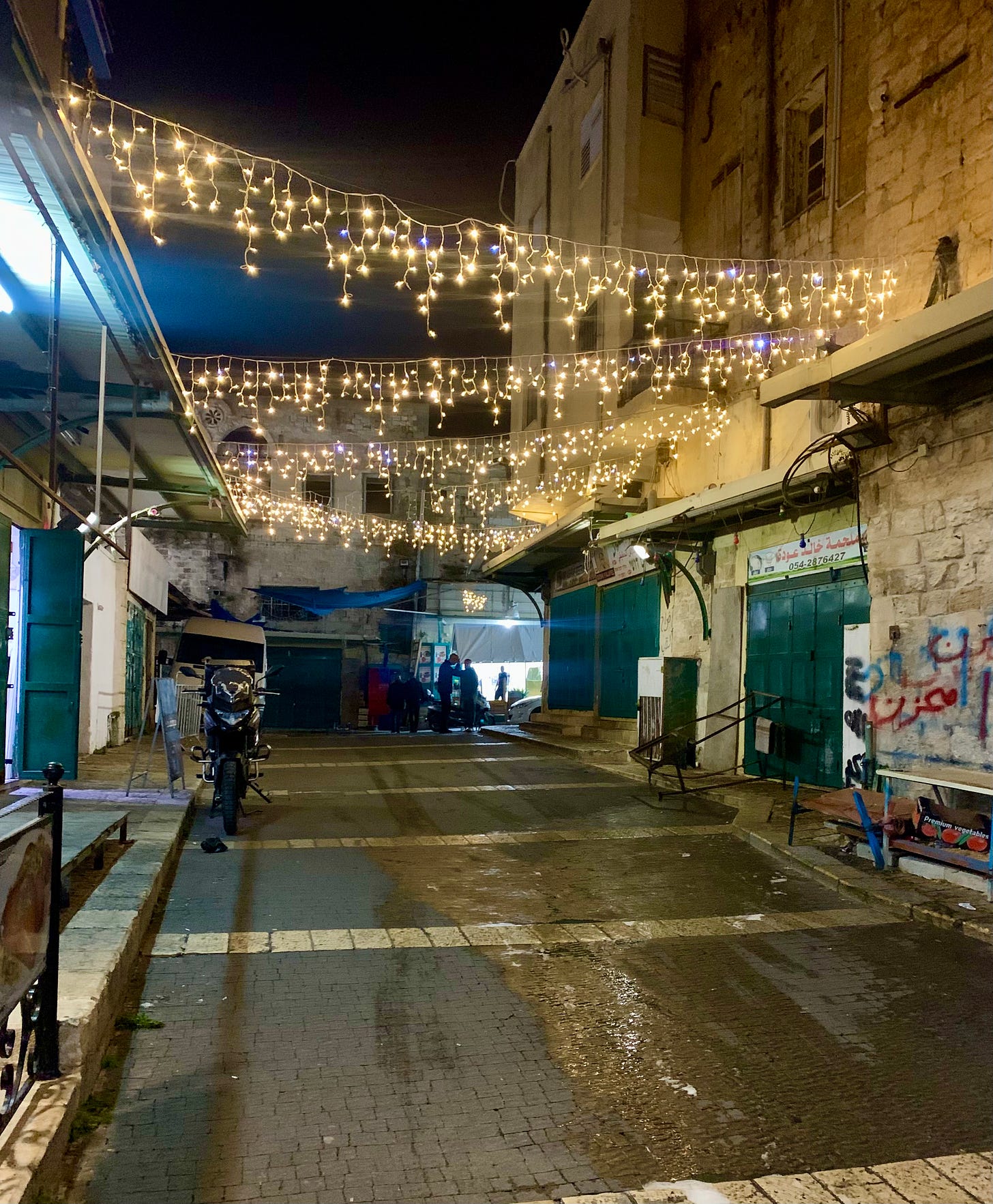 an image of a street in Nazareth Old City, decorated with strings of twinkling lights strung across the cobbled street