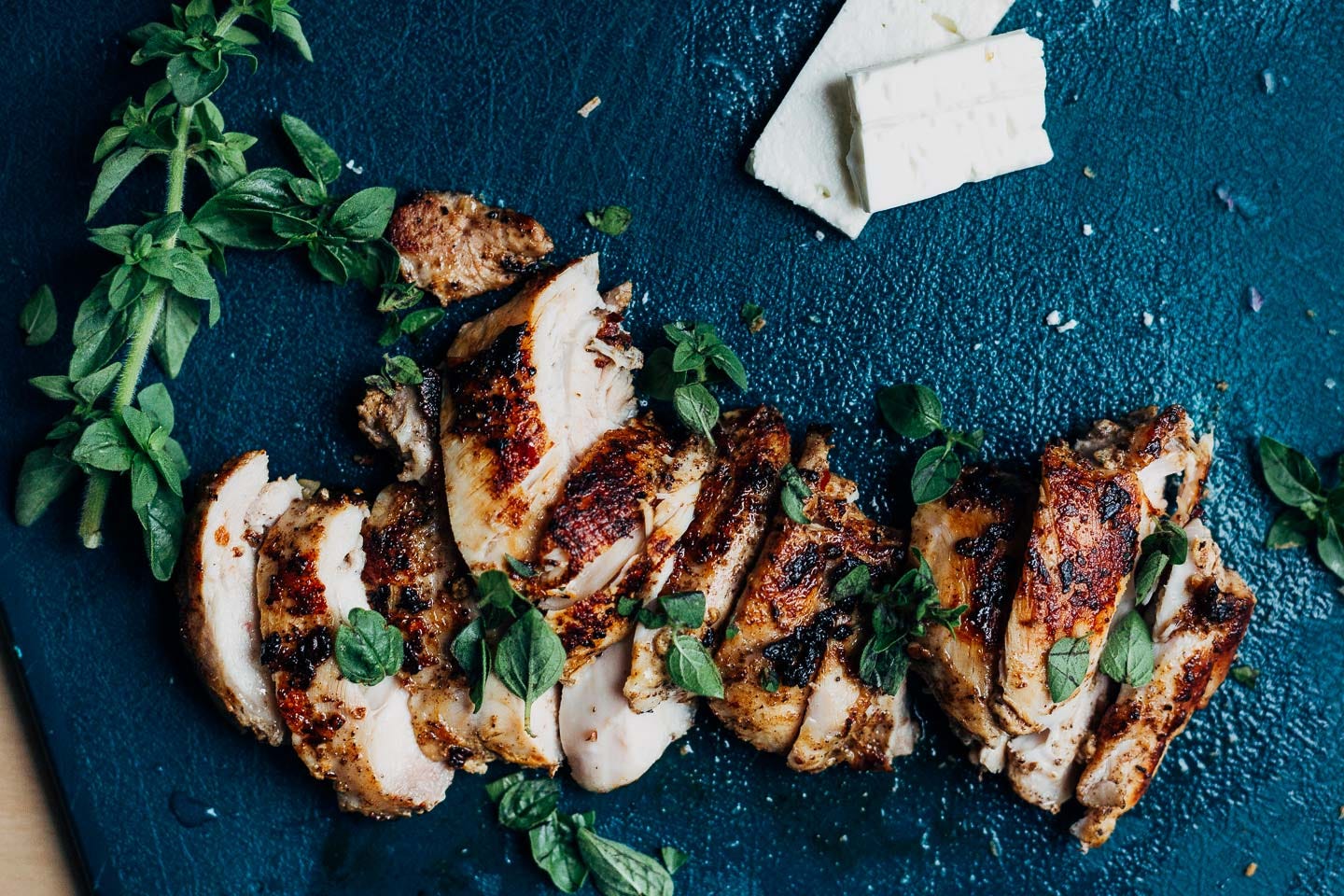 Sliced chicken on a cutting board with herbs.