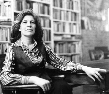 Susan Sontag sitting in front of bookshelves