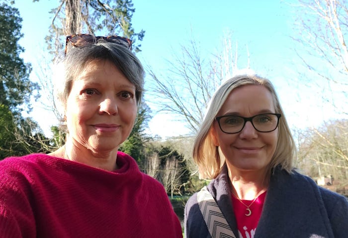 Two women smile at the camera on a sunny winter day