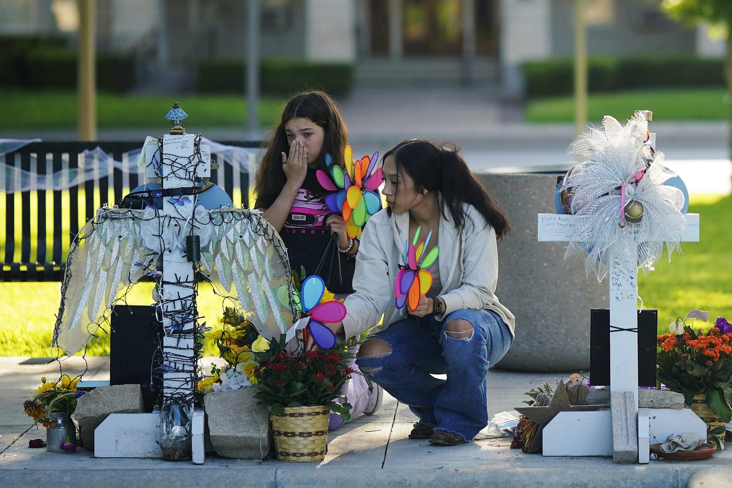 Two people placing colorful pinwheels at a memorial