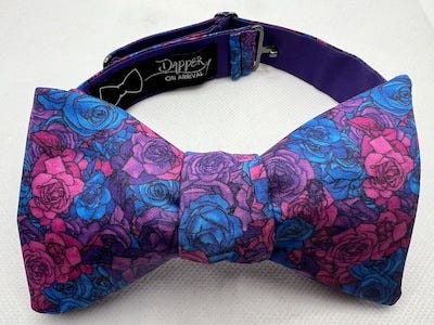 a bow tie covered in a rose pattern in bisexual pride colors