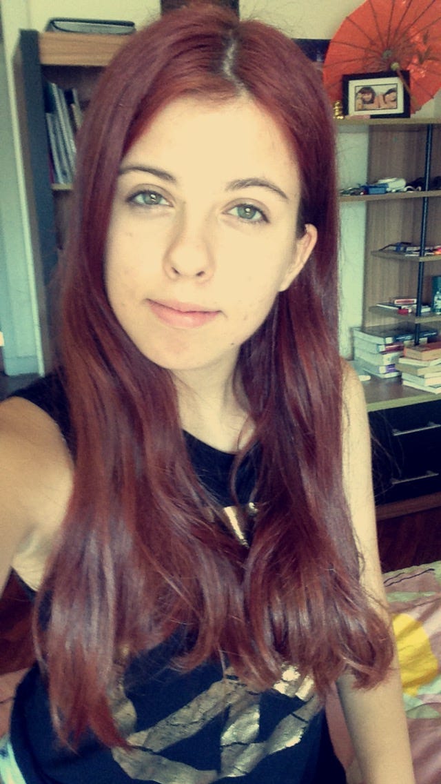 A selfie of teenage Mariya Delano, looking into the camera with a slight smile. She has long, beautiful red hair and her eyes look very bright and green.
