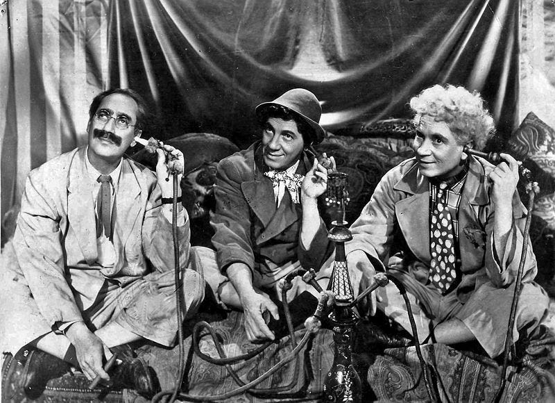 black and white photo of Groucho, Chico, and Harpo Marx, each holding the business end of a hookah to his ear as if it were a telephone