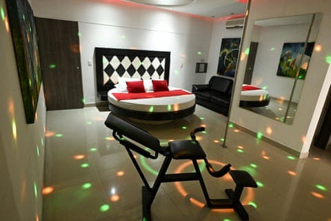 A room with a circular bed, dance pole, mirror, disco lights and a Kama Sutra chair.