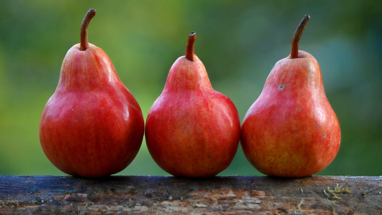 Three red pears sitting beside each other. 