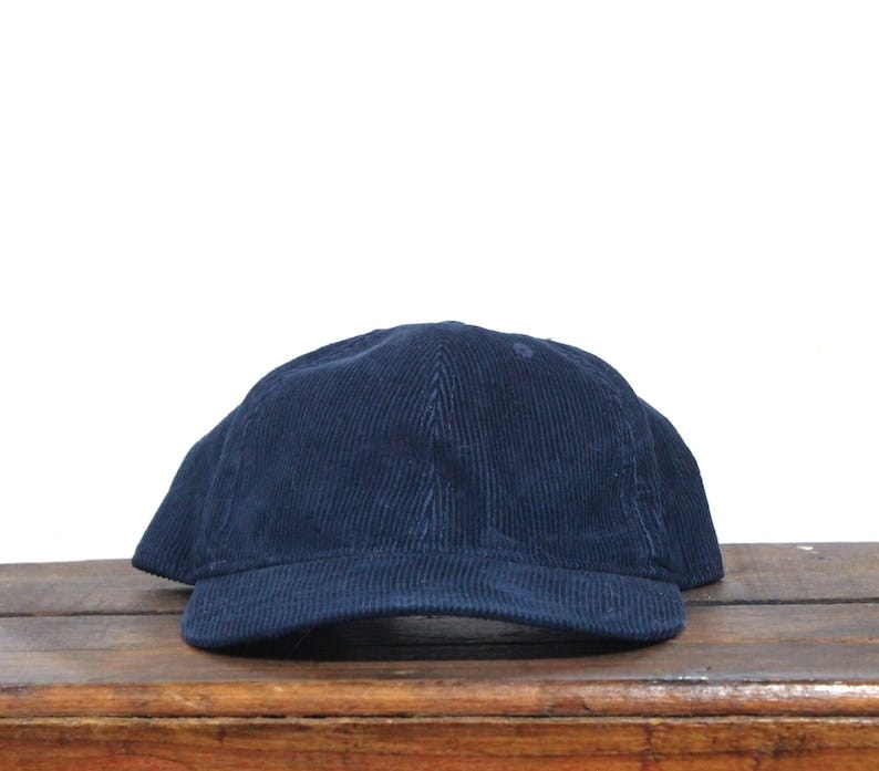 May include: A dark blue corduroy baseball cap