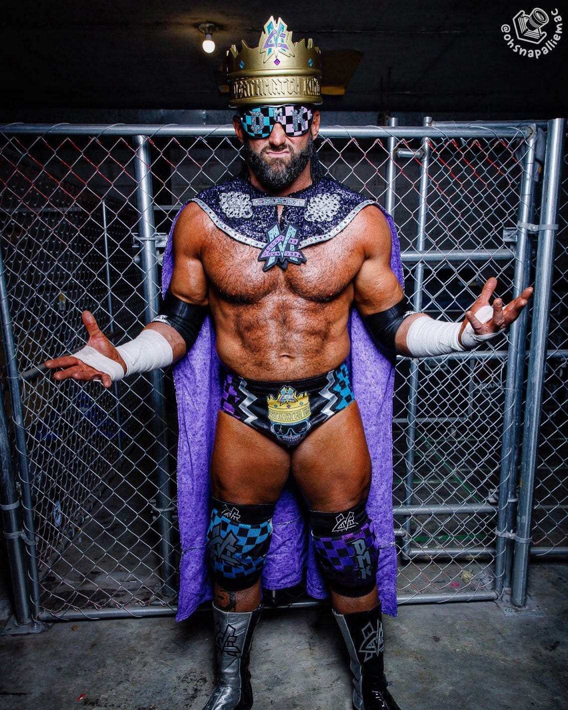 Matt Cardona poses in full "Deathmatch King" regalia in front of a steel cage, positioned back stage at a GCW event in Georgia