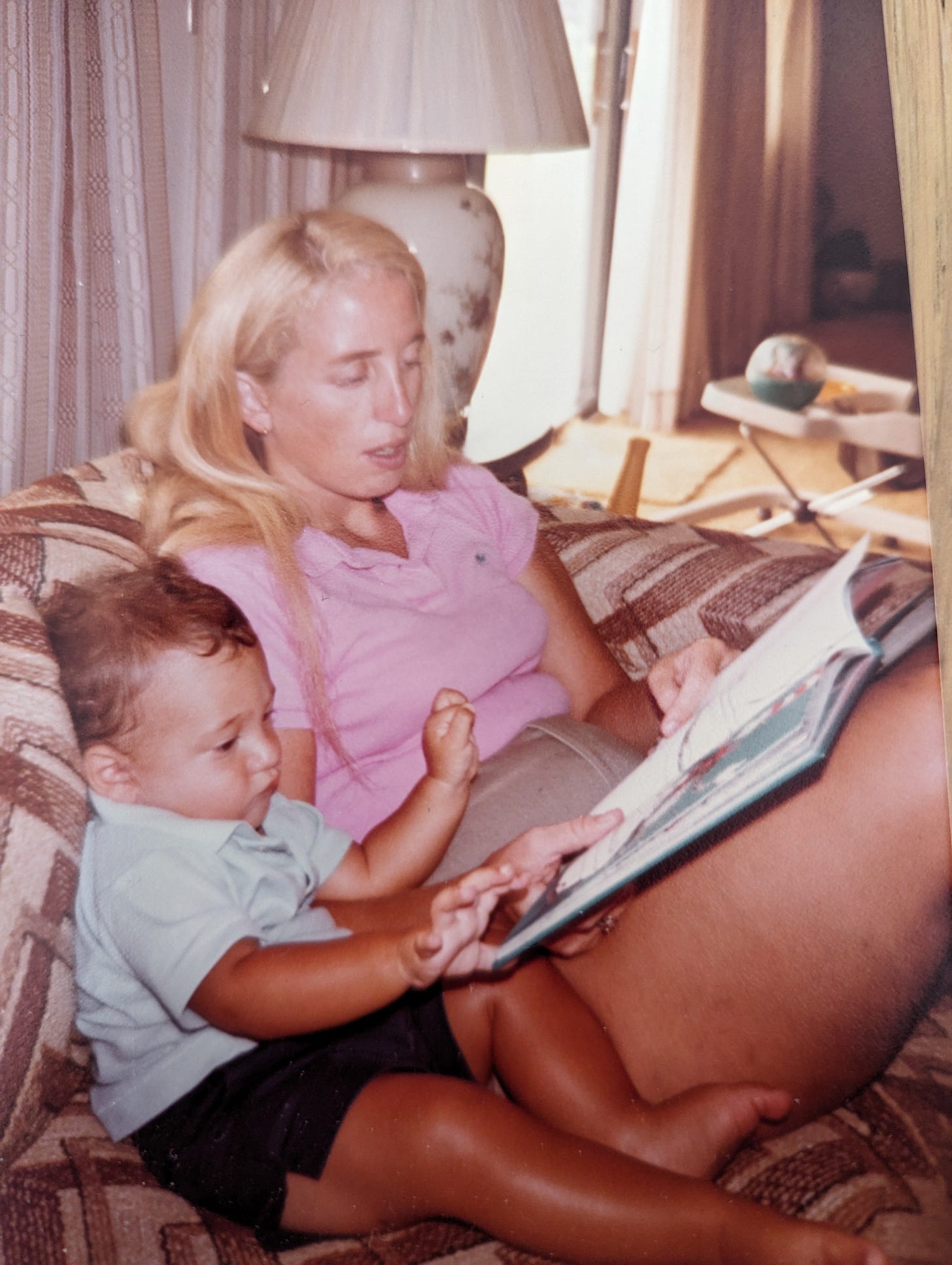 A heartwarming scene of reading time together on a vintage patterned couch.
